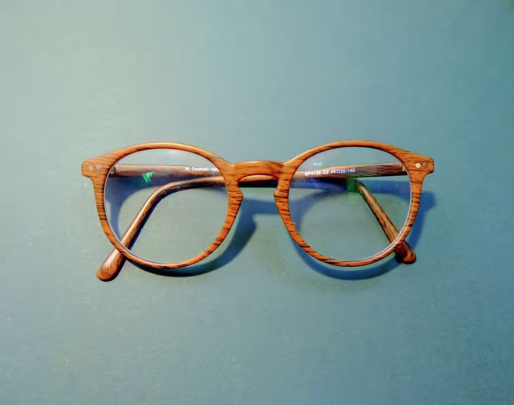 Wooden eyeglasses on a teal background